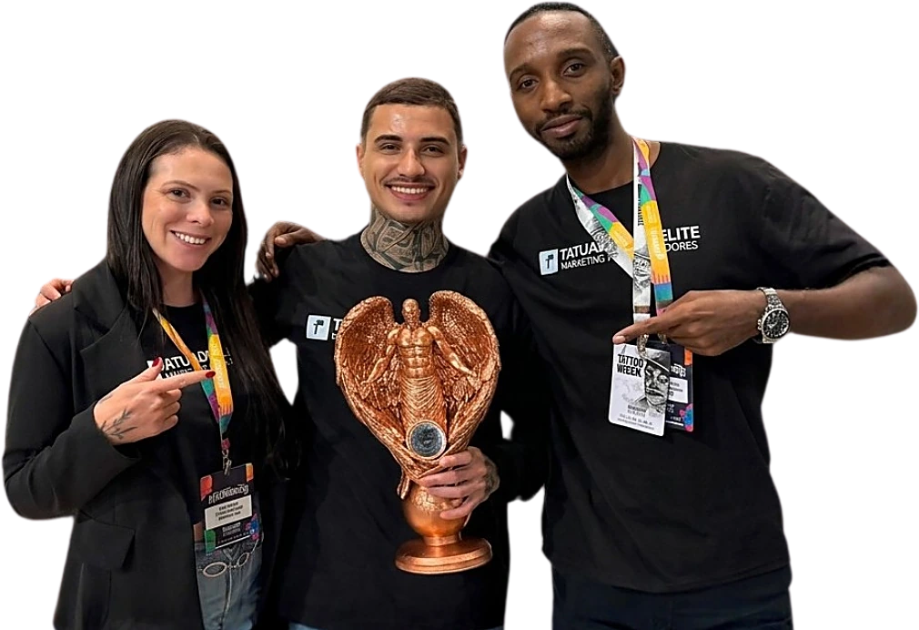 Equipe Castelo Ads — duas pessoas e, ao centro, um homem segurando um troféu dourado em evento de tatuagem